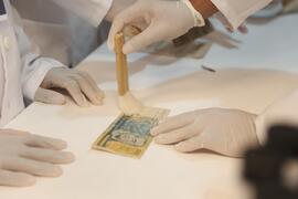 Fotografia de Deivson Sabadini enquanto demonstra a higienização da cédula de cem cruzados