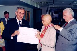 Fotografia da Procuradora de Justiça, Tânia Maria Salles Moreira, recebendo o diploma da medalha ...