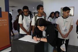 Fotografia dos estudantes do CIEP Carlos Drummond de Andrade durante a assinatura do livro de pre...