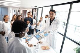 Fotografia de Kevyn Gonçalves entregando o livro "CDM/MPRJ: Há algo novo" aos estudante...