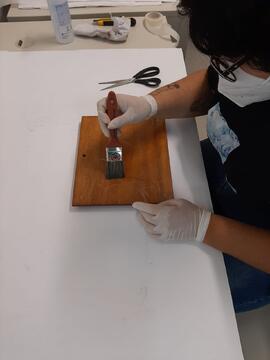 Fotografia da estagiária de museologia do Centro de Memória, Liziane dos Santos, realizando a hig...