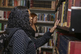 Fotografia de uma aluna da EM República do Peru enquanto observa os livros da Biblioteca Daniel A...